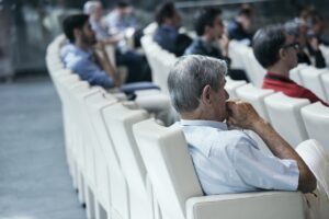 A man in an audience with his hand on his chin, looking as though he is thinking.