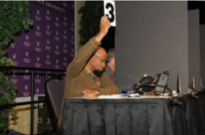 A judge holding up a card with the number three on it.