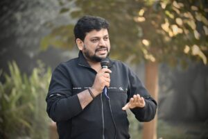A man speaking outside with a microphone in hand.