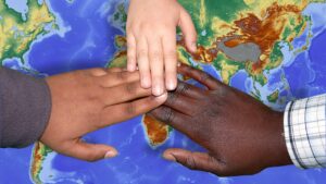 Three hands of different races linking over a map.