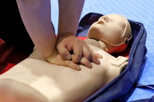 A person practicing CPR on a demonstration dummy.