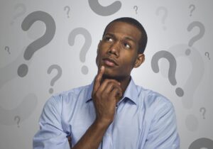 A man pondering, with question marks in the background.