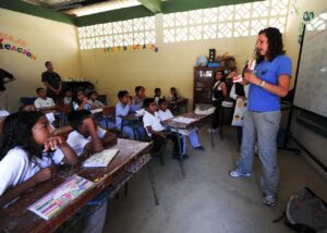 A teacher standing in the front of a classroom talking to a group of students.