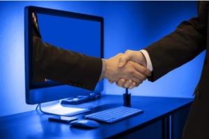 A hand coming out of computer monitor to shake another hand.