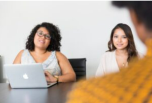 People in an office room, sitting at a table.