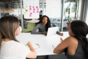 Three people sitting at table in an office setting.