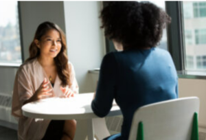 Two women at a table in a business setting.