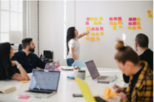 A woman making presentation at work, using sticky notes on a white board.