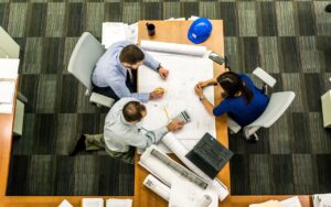 Three people sitting at a table in an office setting.