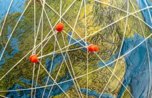 Globe with push pins and string connecting the pins.