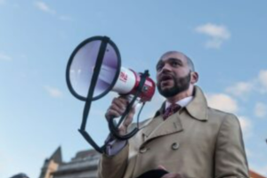 A man with a megaphone speaking outdoors.