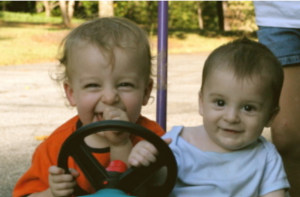 Children smiling in a kiddy car.